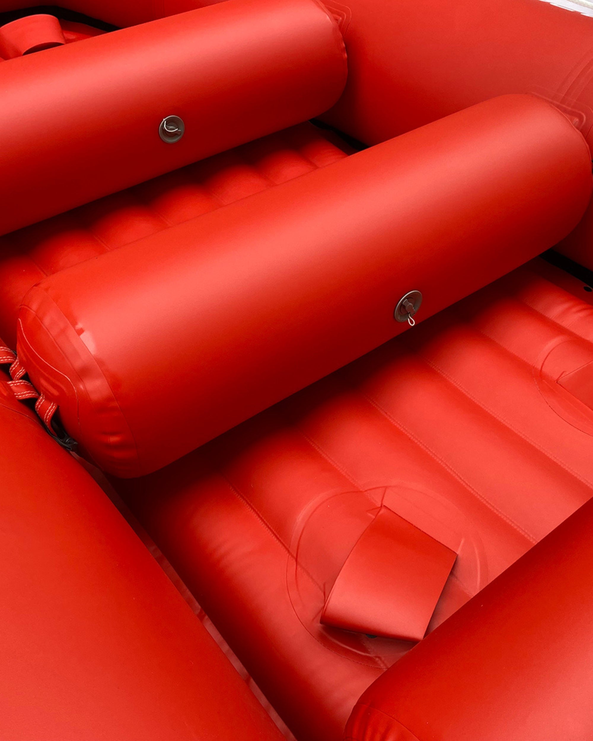 Red inflatable raft with padded bench seats and textured deck floor