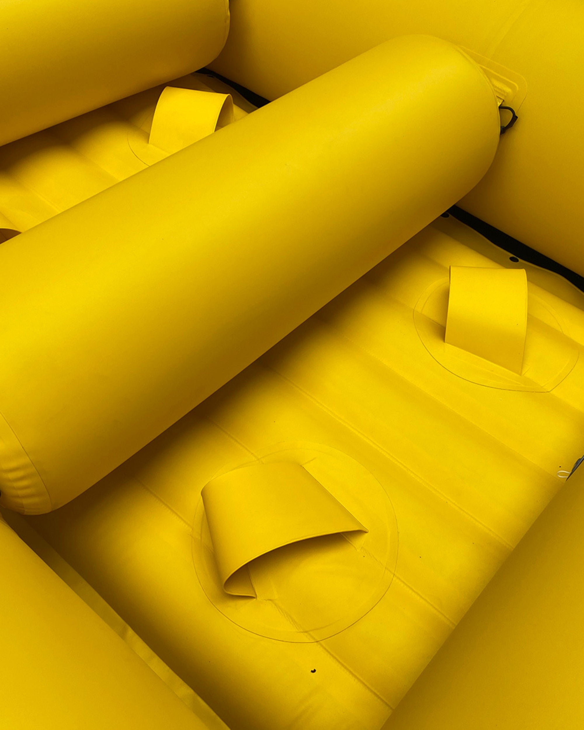 Close-up of yellow inflatable raft seat tubes and molded footrest area