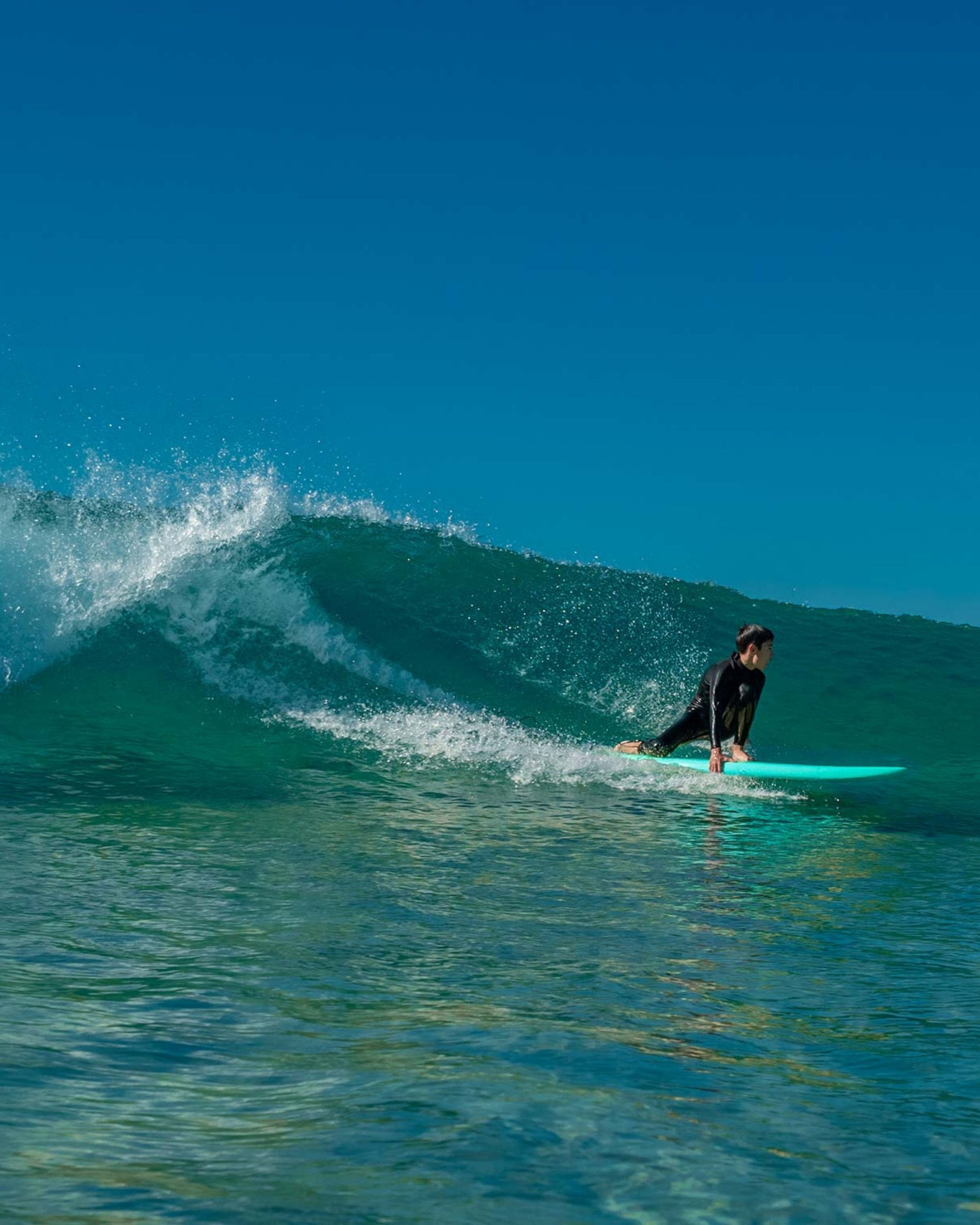 Blue surfboard on the wave with surfer kneeling