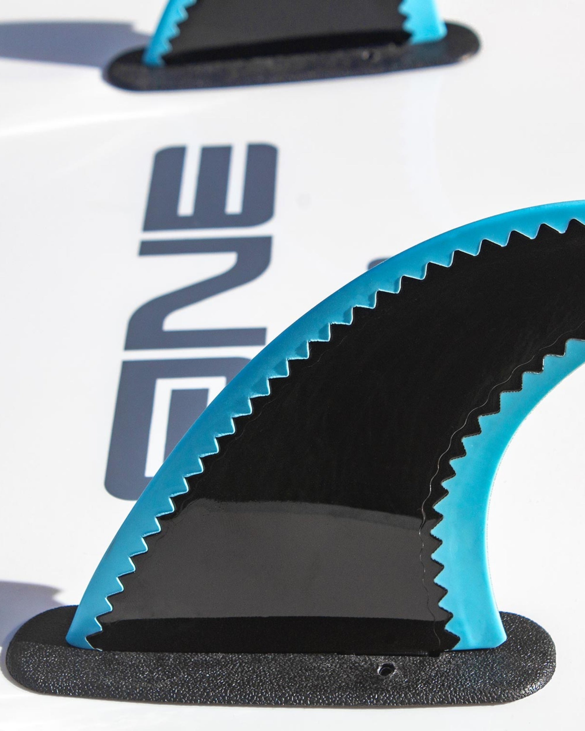 Blue surfboard fins close-up with black fin base and “9” logo on board